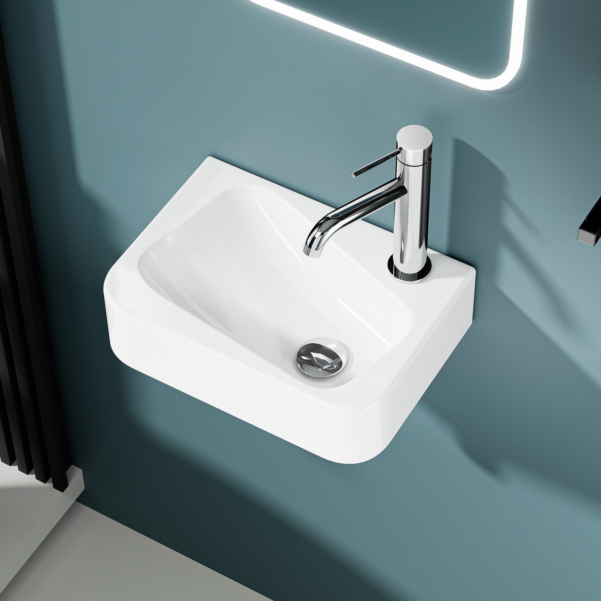 Lavabo mural blanc asymétrique avec robinet chromé et trou de trop-plein sur mur cyan.