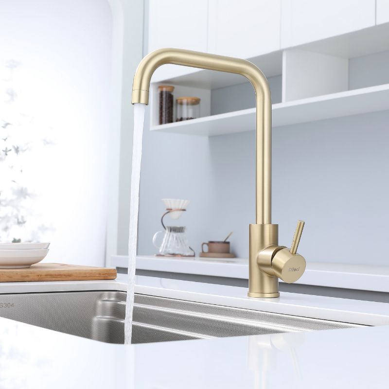 Robinet de cuisine doré au design intemporel. Bec à grand arc, base cylindrique et évier en acier inoxydable.