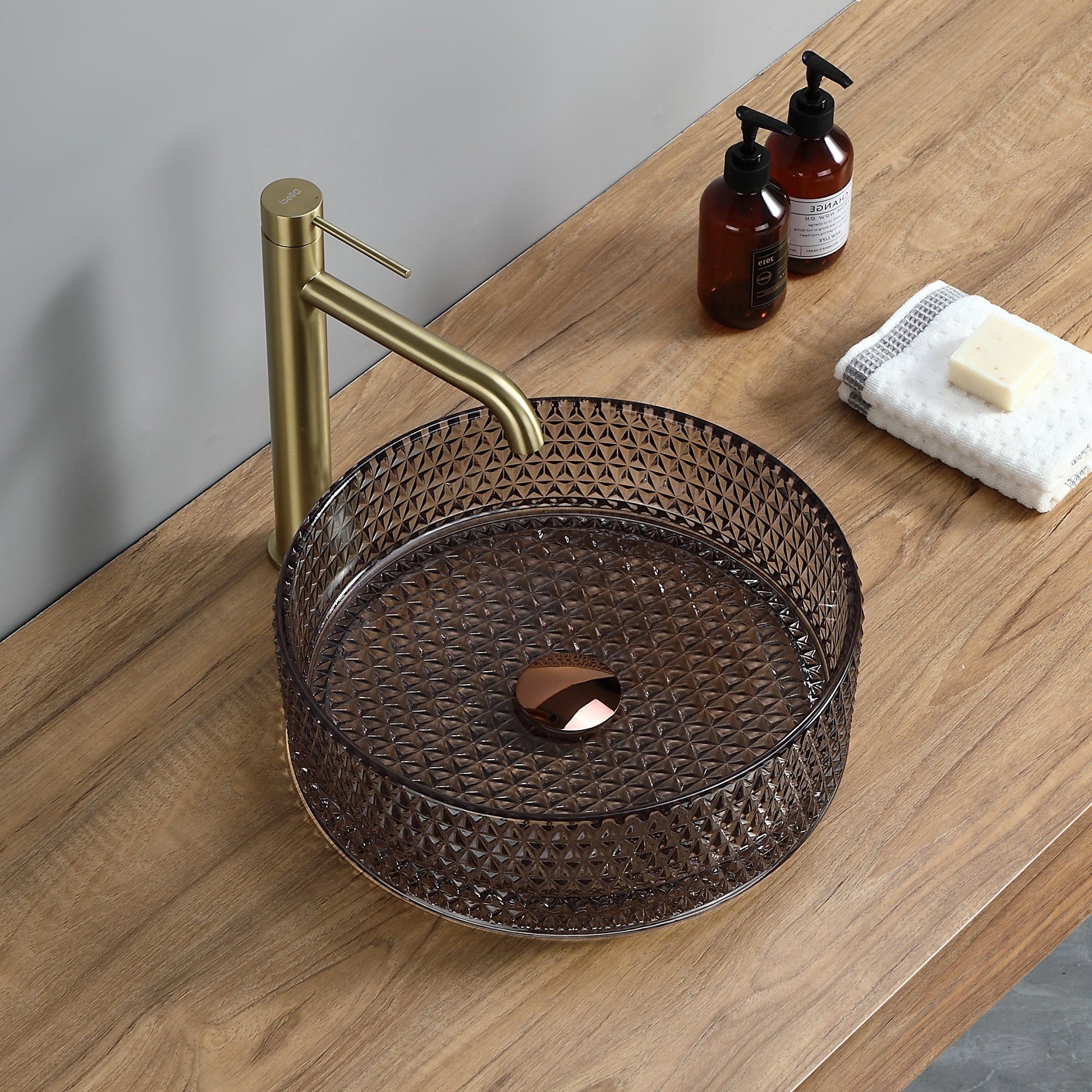 Vasque ronde en verre fumé (36 cm de diamètre), à motif géométrique, avec robinetterie dorée.