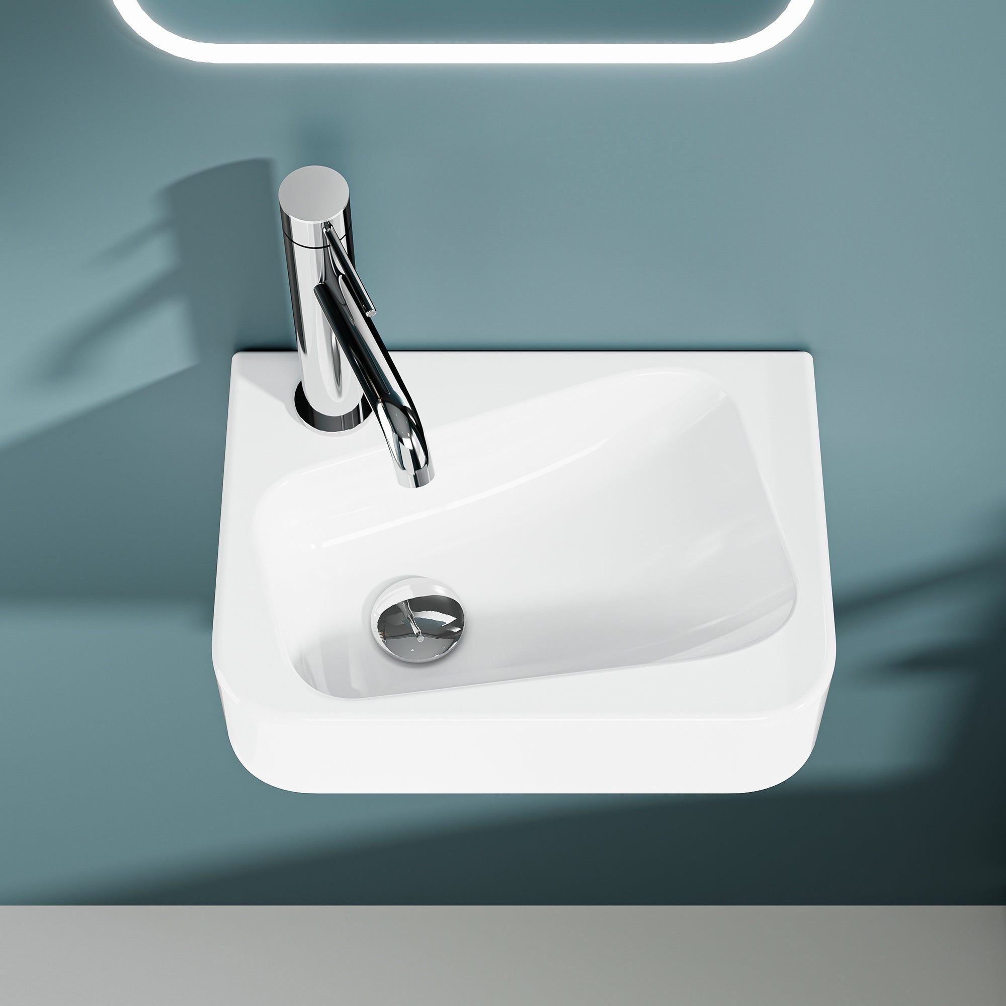 Lave-mains murale en céramique blanche avec robinet chromé, modèle asymétrique avec sortie gauche.