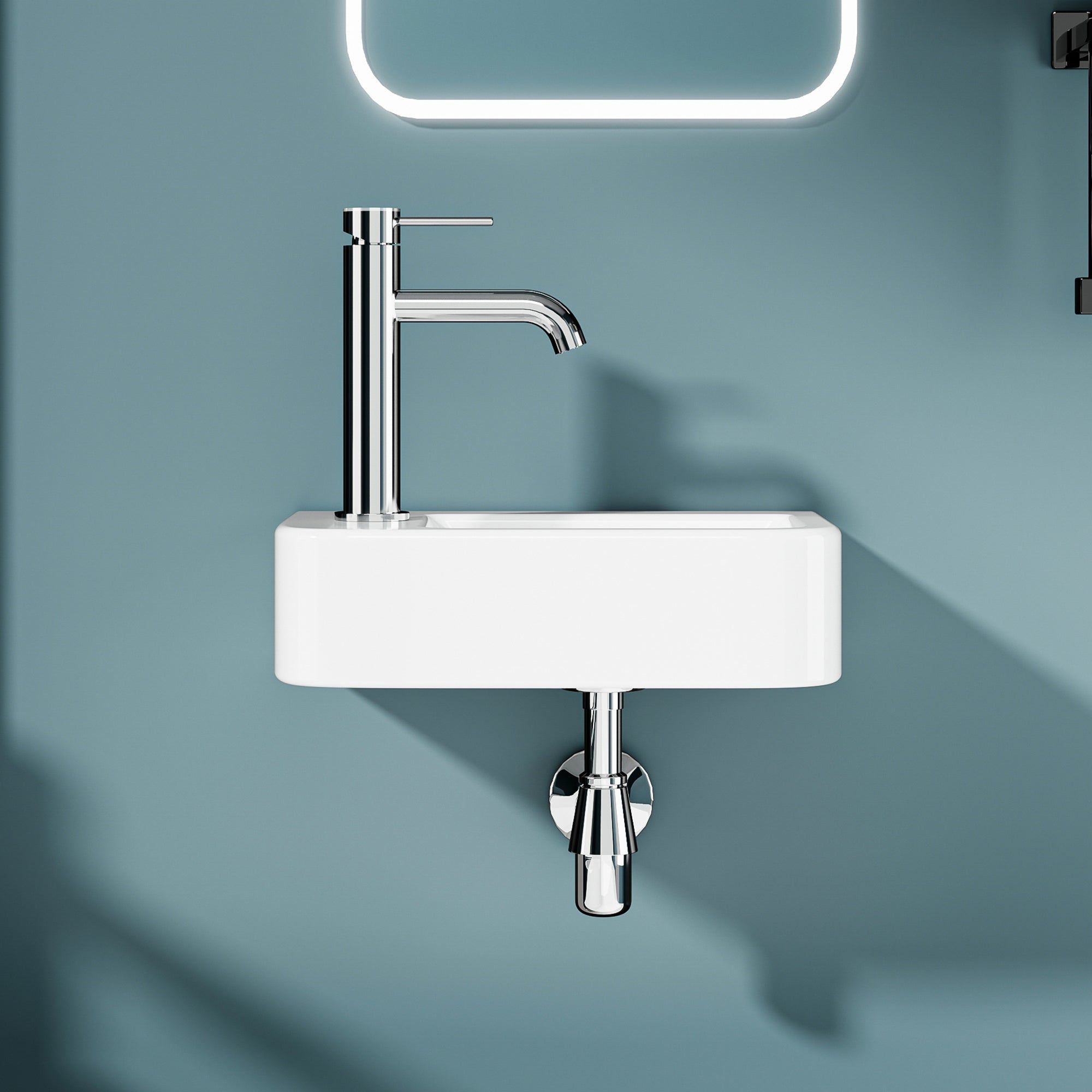 Lave-mains murale compacte en céramique blanche avec robinet en chrome fixée au mur.
